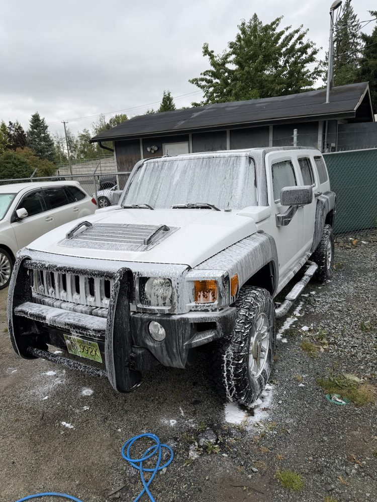 A Hummer H3 covered in snow foam during a wash